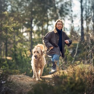 Kvinde er ude og gå tur i skoven med sin hund